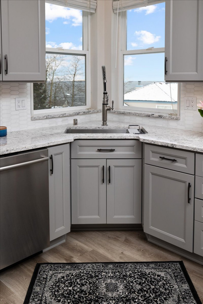 Inspiration for a mid-sized transitional laminate floor and gray floor open concept kitchen remodel with recessed-panel cabinets, gray cabinets, quartz countertops, white backsplash, marble backsplash, stainless steel appliances and white countertops