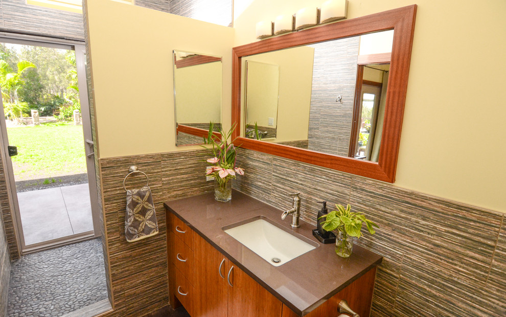 This is an example of a mid-sized tropical bathroom in Hawaii with an undermount sink, flat-panel cabinets, light wood cabinets, engineered quartz benchtops, a corner shower, gray tile, ceramic tile and yellow walls.