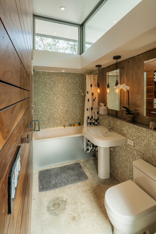This is an example of a small modern master bathroom in Houston with a pedestal sink, engineered quartz benchtops, a drop-in tub, a two-piece toilet, glass tile, concrete floors and green tile.