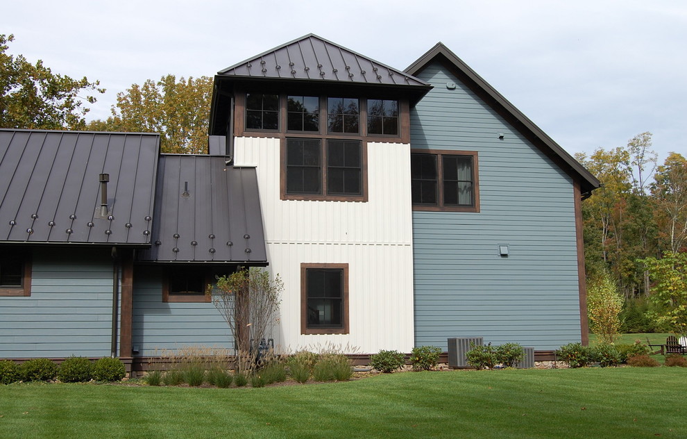 This is an example of a large eclectic two-storey blue house exterior in New York with a gable roof, a metal roof and wood siding.