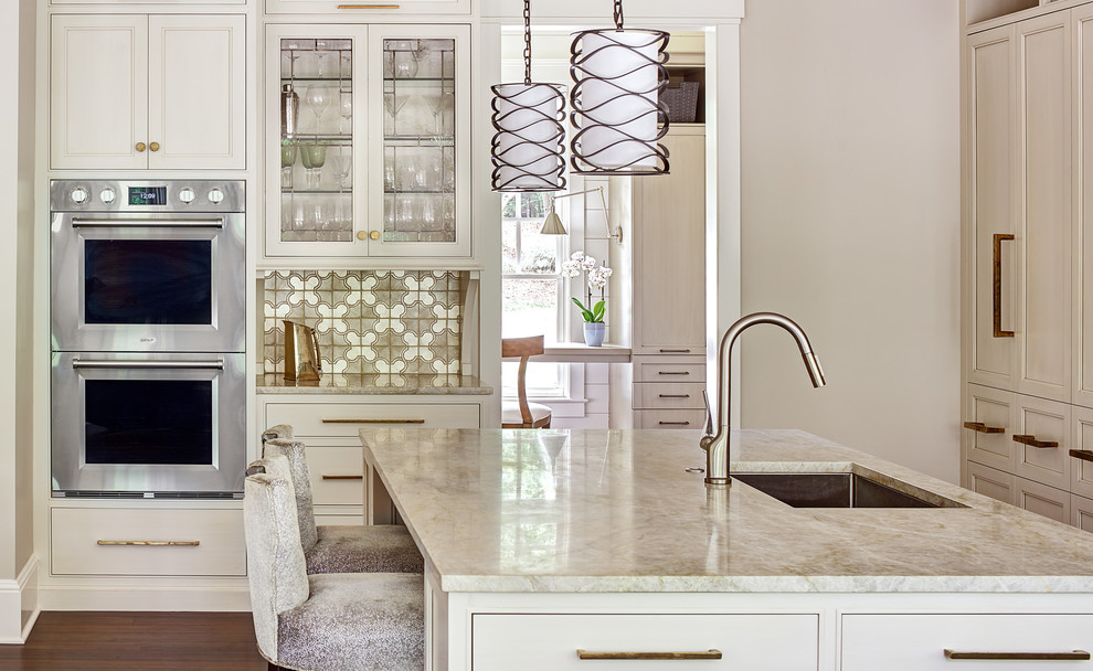 Inspiration for a mid-sized transitional l-shaped eat-in kitchen in Charlotte with a single-bowl sink, recessed-panel cabinets, beige cabinets, quartzite benchtops, metallic splashback, terra-cotta splashback, stainless steel appliances, medium hardwood floors, with island and brown floor.