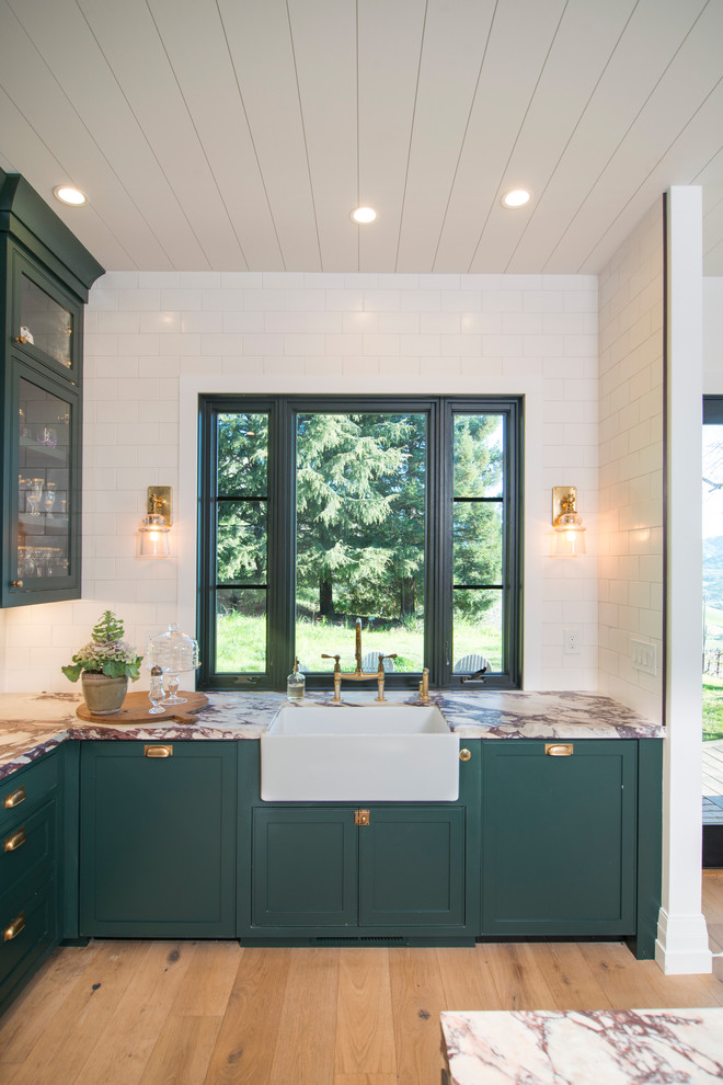 This is an example of a large country galley eat-in kitchen in San Francisco with a drop-in sink, flat-panel cabinets, green cabinets, marble benchtops, white splashback, ceramic splashback, stainless steel appliances, medium hardwood floors, with island, brown floor and white benchtop.