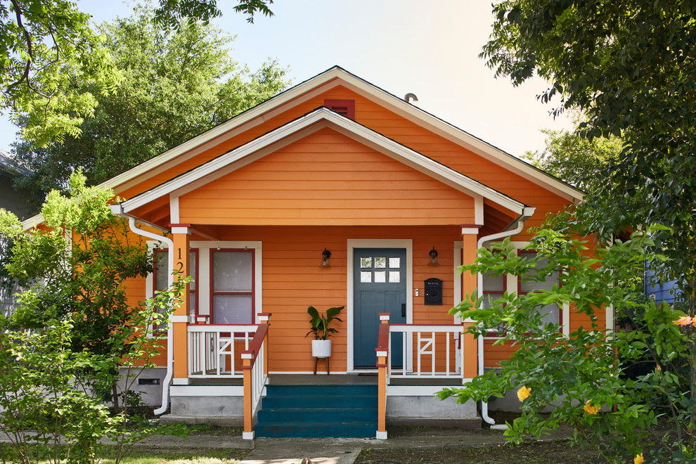 Photo of a mid-sized eclectic one-storey orange house exterior in Austin with wood siding and a gable roof.
