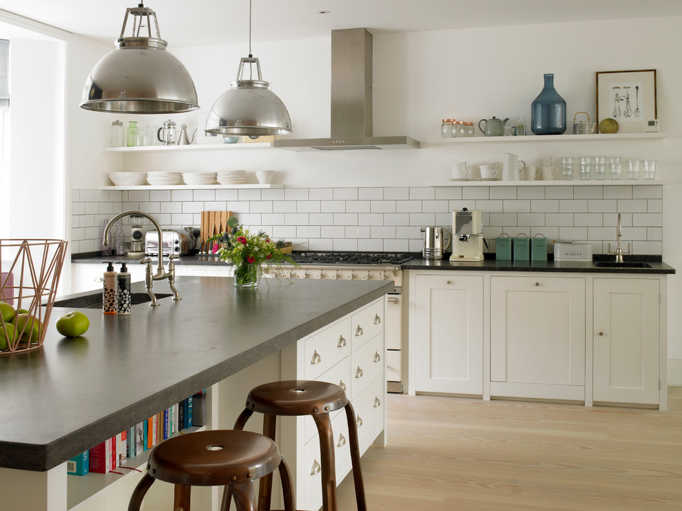Inspiration for a mid-sized transitional u-shaped eat-in kitchen in London with white cabinets, white splashback, subway tile splashback, a drop-in sink, shaker cabinets, limestone benchtops, panelled appliances, light hardwood floors, with island, beige floor and grey benchtop.