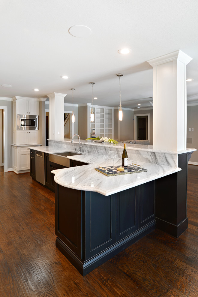 Inspiration for a large transitional single-wall dark wood floor eat-in kitchen remodel in Dallas with a farmhouse sink, shaker cabinets, white cabinets, marble countertops, beige backsplash, glass tile backsplash, stainless steel appliances and an island