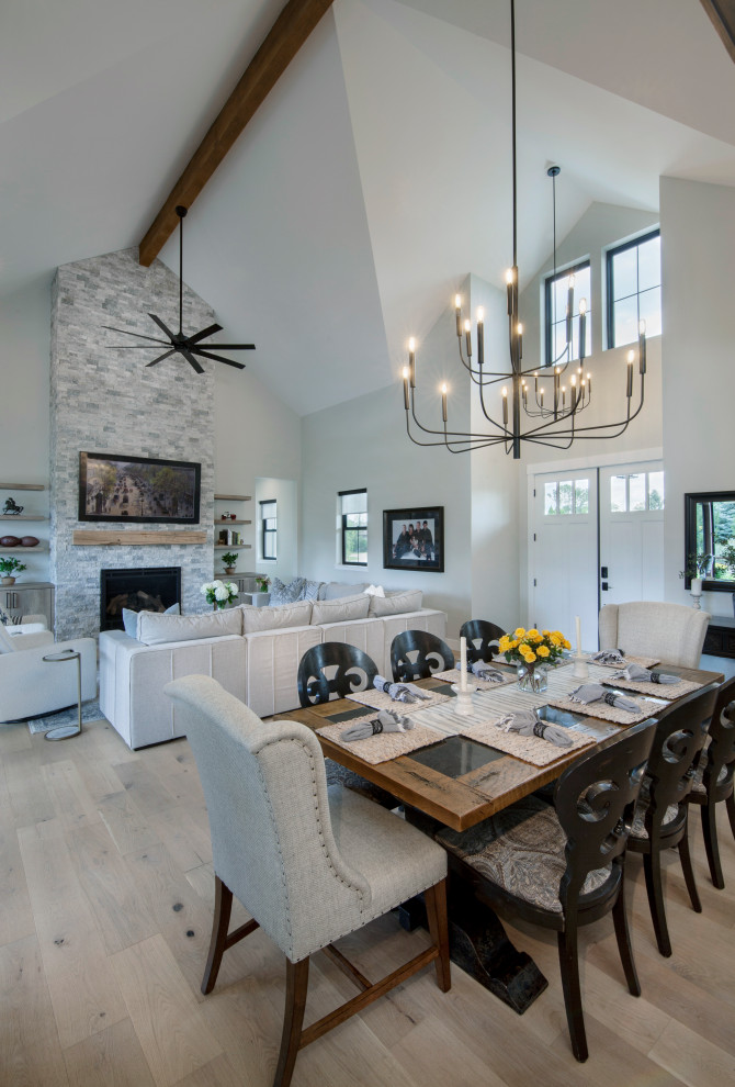 This is an example of a large country open plan dining in Denver with grey walls, light hardwood floors, a standard fireplace, brown floor and vaulted.