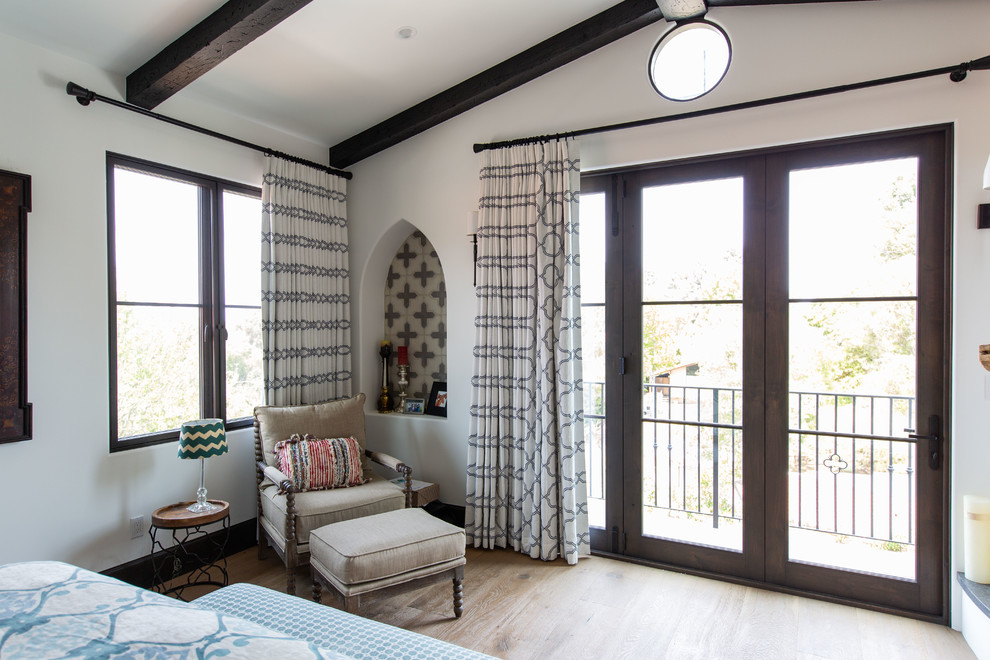 Mediterranean master bedroom in Los Angeles with light hardwood floors.