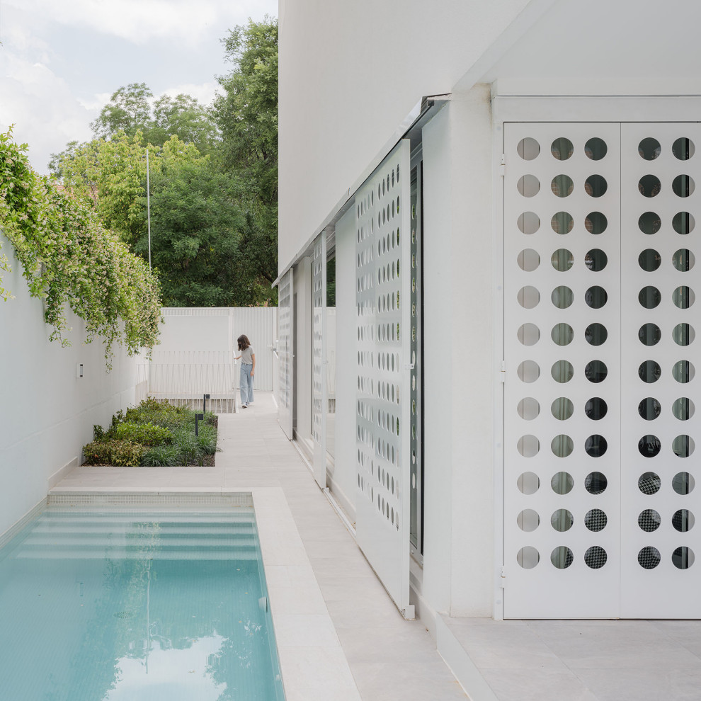 Foto de piscina alargada actual de tamaño medio rectangular en patio lateral