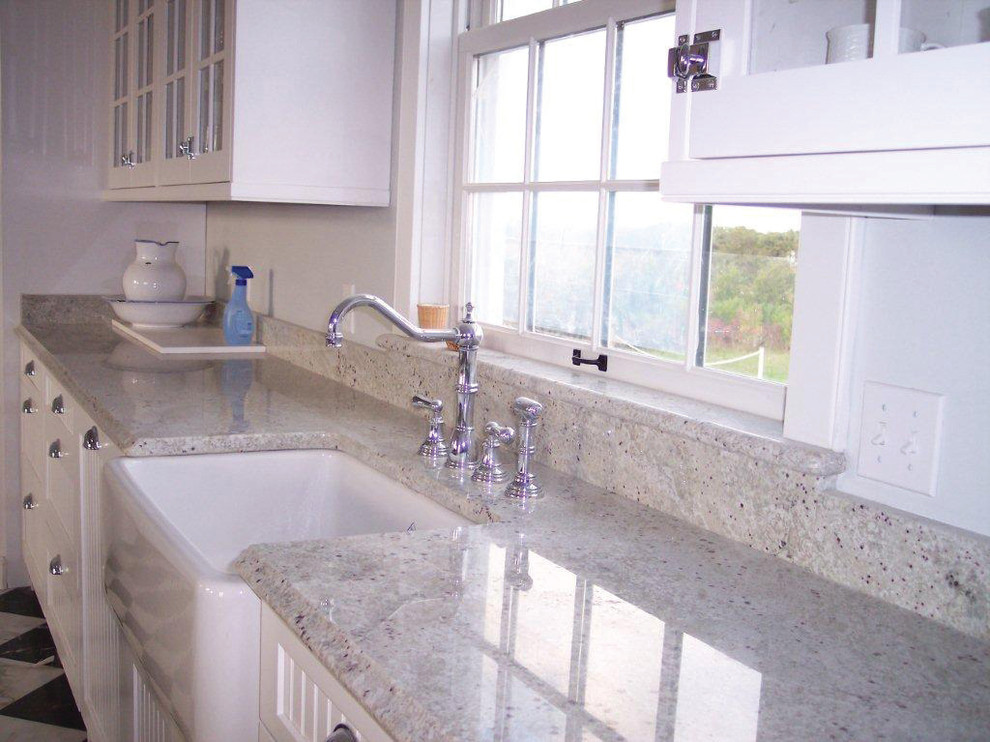 Example of a mid-sized transitional vinyl floor and black floor kitchen design in Boston with a farmhouse sink, glass-front cabinets, white cabinets, granite countertops and white backsplash