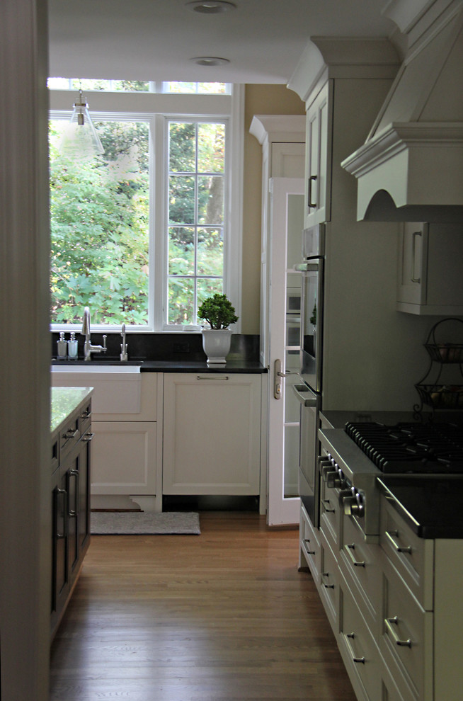 Large transitional u-shaped medium tone wood floor eat-in kitchen photo in DC Metro with a farmhouse sink, recessed-panel cabinets, white cabinets, quartzite countertops, white backsplash, mosaic tile backsplash, stainless steel appliances and an island