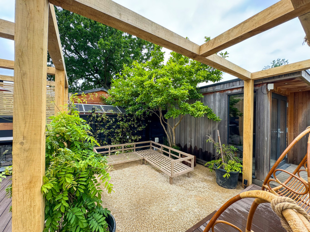 Geometrischer, Großer, Halbschattiger Moderner Kiesgarten im Sommer, hinter dem Haus mit Gehweg und Holzzaun in London
