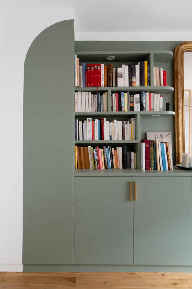 Cette photo montre une salle de séjour tendance de taille moyenne avec une bibliothèque ou un coin lecture, un mur vert, parquet clair et aucun téléviseur.