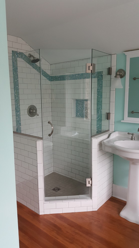 Small arts and crafts master bathroom in Cedar Rapids with beaded inset cabinets, white cabinets, a drop-in tub, a corner shower, a two-piece toilet, multi-coloured tile, mosaic tile, green walls, medium hardwood floors, a pedestal sink, brown floor and a hinged shower door.