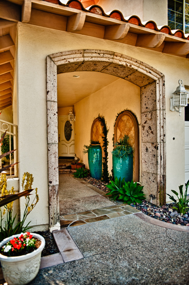 Small mediterranean courtyard shaded xeriscape in Orange County with a container garden and river rock for spring.