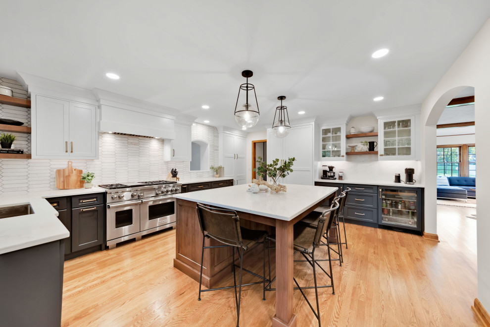 Enclosed kitchen - large transitional l-shaped medium tone wood floor and brown floor enclosed kitchen idea in Columbus with a single-bowl sink, flat-panel cabinets, white cabinets, quartz countertops, white backsplash, terra-cotta backsplash, paneled appliances, an island and white countertops