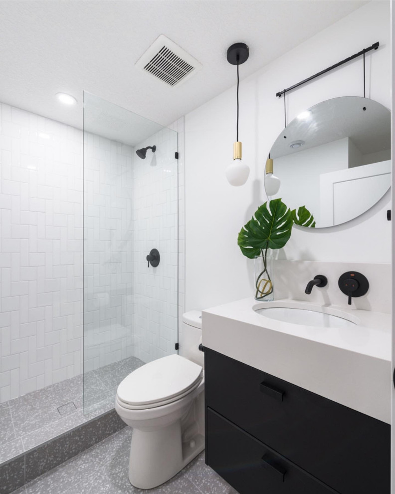 Источник вдохновения для домашнего уюта: маленькая ванная комната в стиле ретро с стеклянными фасадами, черными фасадами, открытым душем, раздельным унитазом, белой плиткой, керамогранитной плиткой, белыми стенами, полом из керамогранита, душевой кабиной, врезной раковиной, столешницей из искусственного кварца, серым полом, душем с распашными дверями, белой столешницей, тумбой под одну раковину и подвесной тумбой для на участке и в саду