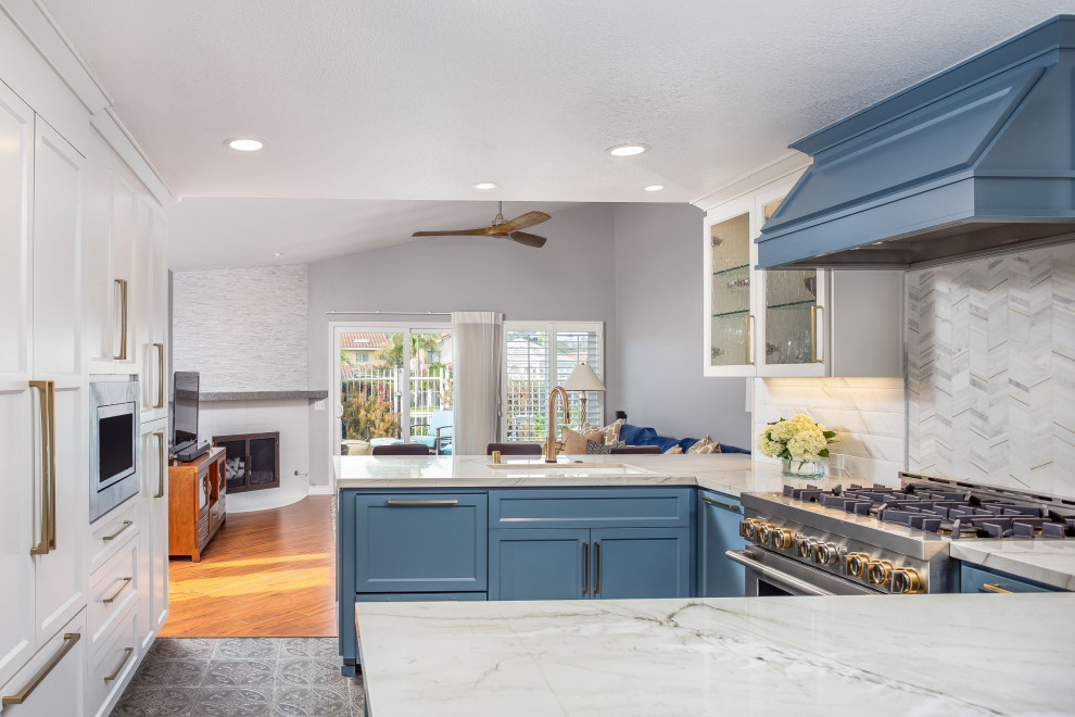 Photo of a large beach style u-shaped eat-in kitchen in San Diego with an undermount sink, raised-panel cabinets, blue cabinets, quartz benchtops, multi-coloured splashback, ceramic splashback, stainless steel appliances, ceramic floors, multi-coloured floor and white benchtop.
