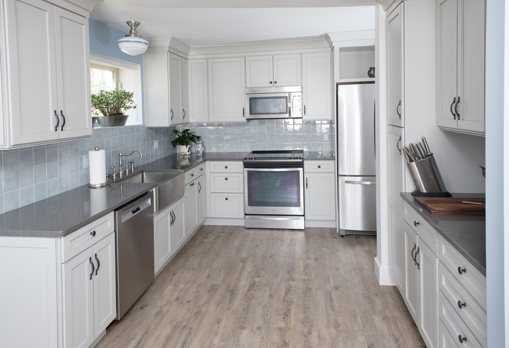Design ideas for a mid-sized transitional l-shaped separate kitchen in Seattle with a farmhouse sink, shaker cabinets, white cabinets, quartz benchtops, blue splashback, ceramic splashback, stainless steel appliances, light hardwood floors and no island.