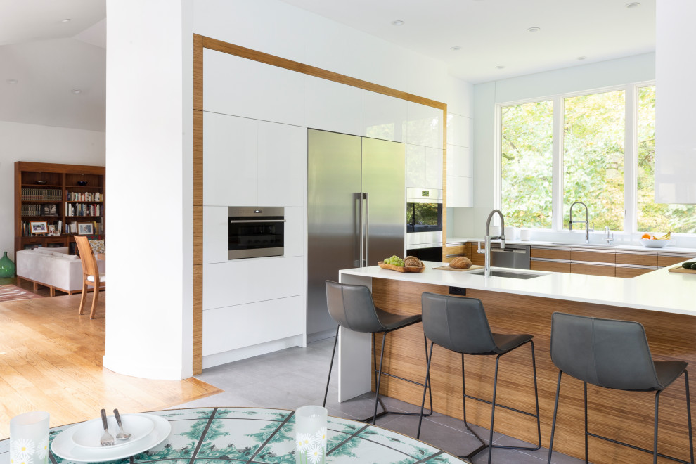 Large contemporary u-shaped eat-in kitchen in New York with flat-panel cabinets, white cabinets, quartz benchtops, white splashback, stone slab splashback, stainless steel appliances, porcelain floors, a peninsula, grey floor and yellow benchtop.