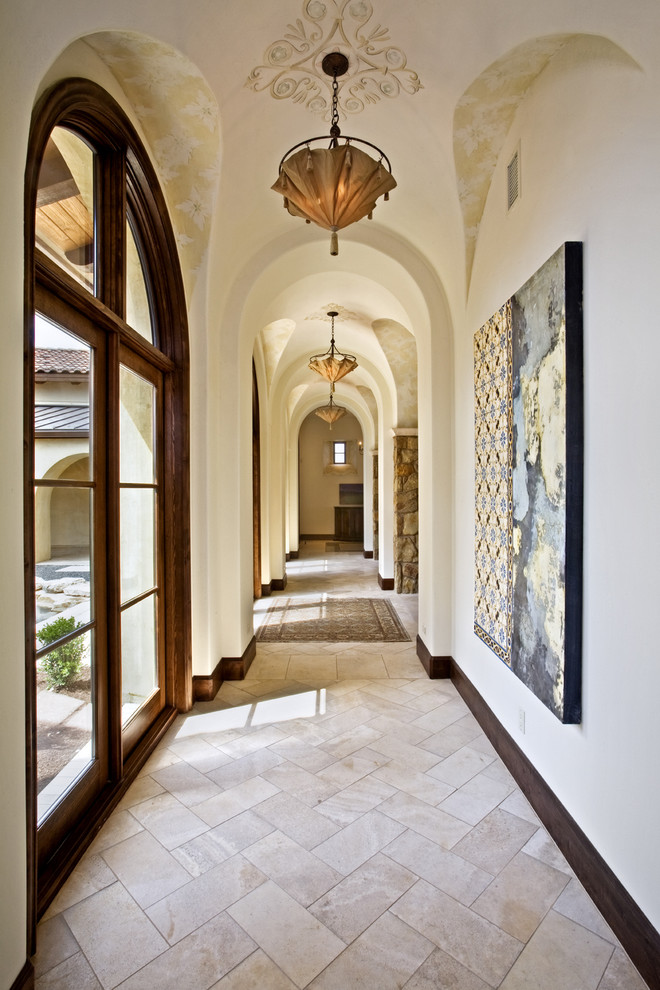 Design ideas for a mediterranean hallway in Austin with white walls and beige floor.