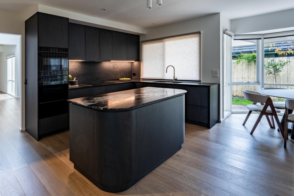 Design ideas for a mid-sized contemporary kitchen in Melbourne with marble benchtops, black splashback, engineered quartz splashback, black appliances and with island.