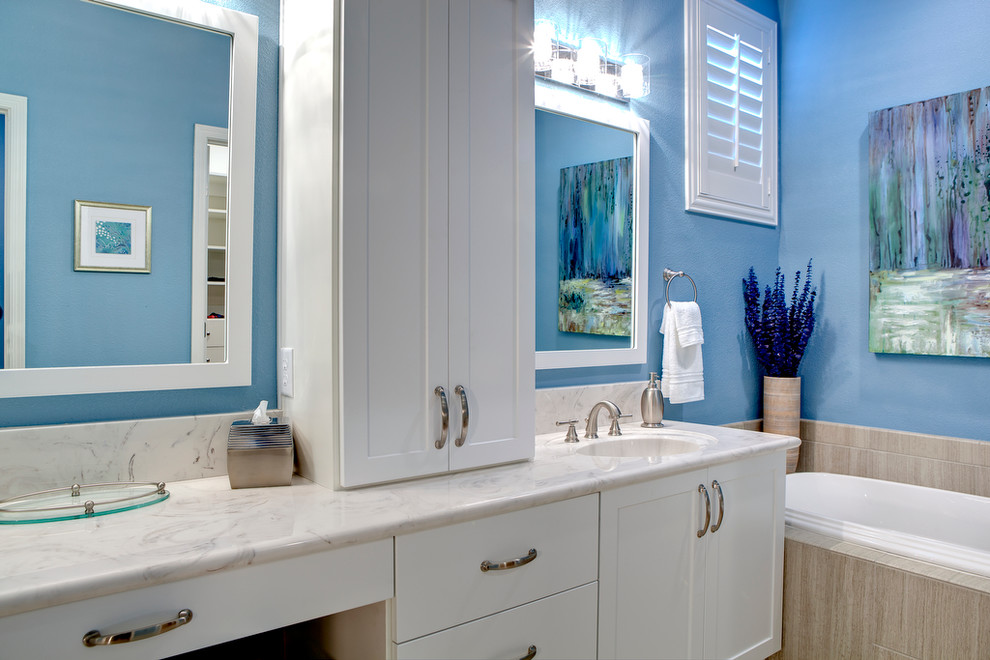 Design ideas for a mid-sized contemporary master bathroom in Las Vegas with an undermount sink, shaker cabinets, white cabinets, marble benchtops, a drop-in tub, blue walls and porcelain floors.
