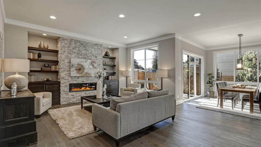 Design ideas for a large transitional open concept family room with grey walls, a standard fireplace, a stone fireplace surround, no tv, grey floor and laminate floors.