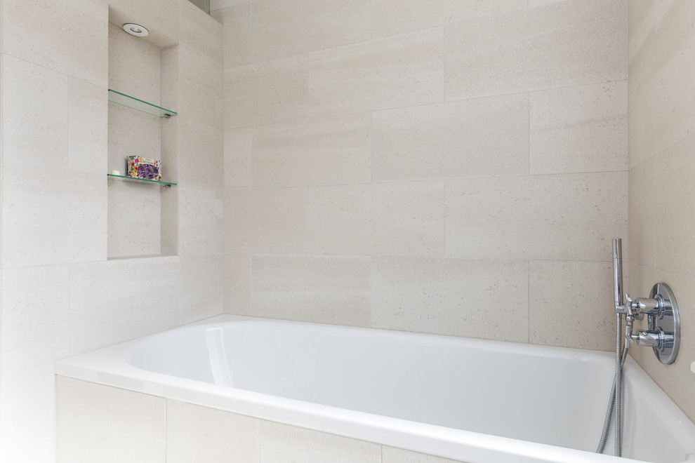 This is an example of a small contemporary kids bathroom in London with flat-panel cabinets, white cabinets, a drop-in tub, an open shower, a wall-mount toilet, beige tile, porcelain tile, beige walls, porcelain floors, a drop-in sink, quartzite benchtops, beige floor and a sliding shower screen.