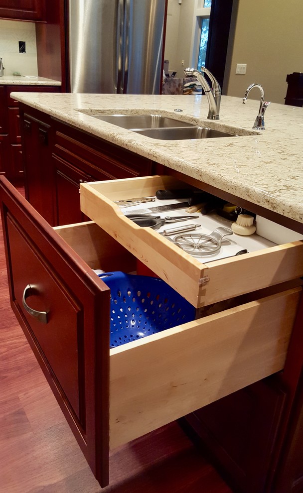 Example of a large transitional u-shaped medium tone wood floor eat-in kitchen design with a double-bowl sink, raised-panel cabinets, medium tone wood cabinets, granite countertops, beige backsplash, ceramic backsplash, stainless steel appliances and an island