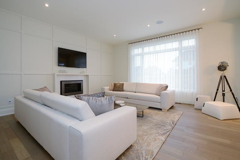 This is an example of a large contemporary formal open concept living room in Toronto with white walls, dark hardwood floors, a standard fireplace, a wall-mounted tv and brown floor.