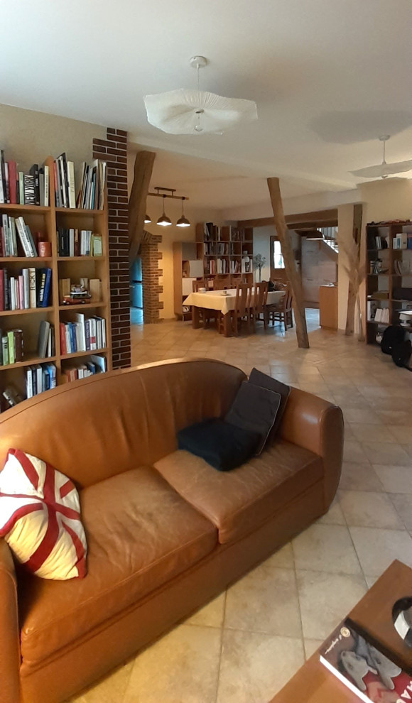Bild på ett mellanstort lantligt allrum med öppen planlösning, med ett bibliotek, vita väggar, travertin golv och beiget golv