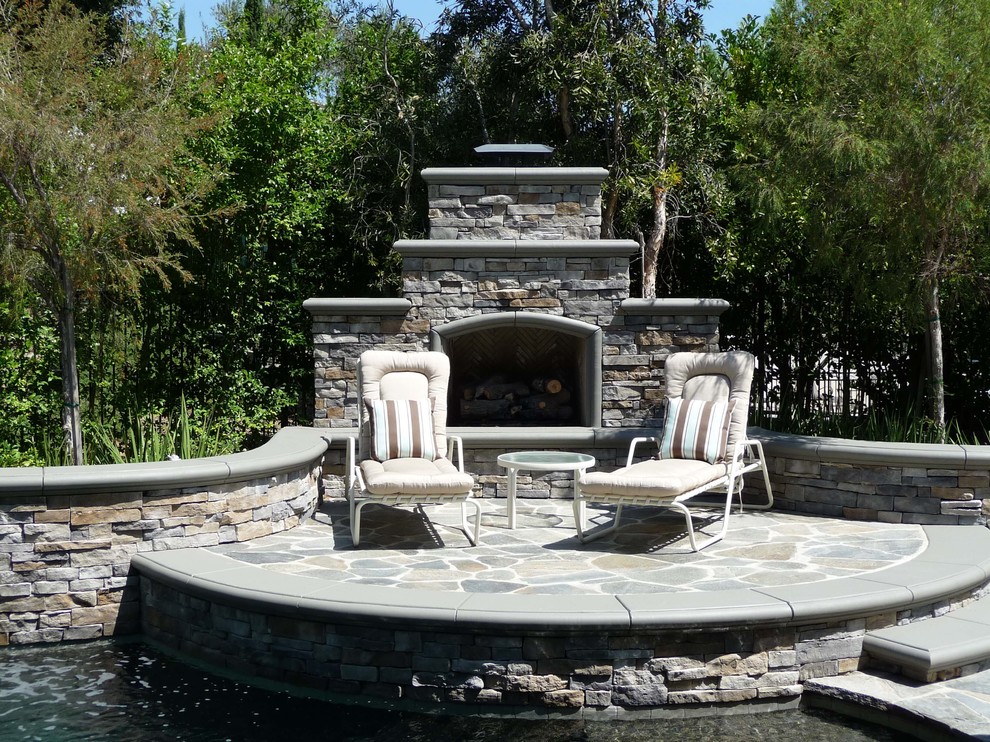 This is an example of a mid-sized traditional backyard patio in Orange County with a fire feature and natural stone pavers.
