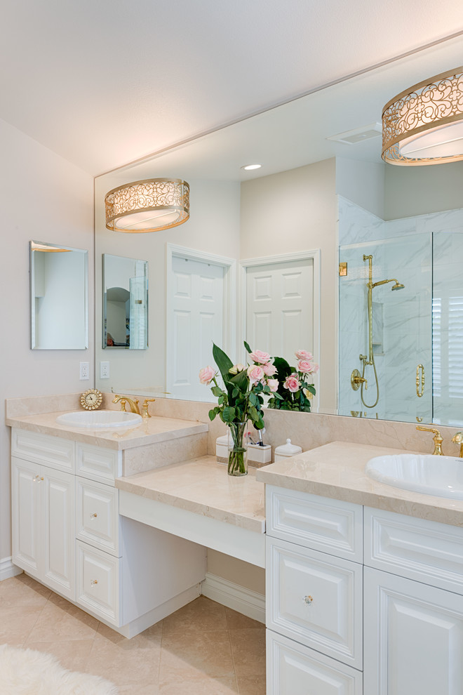 Inspiration for a large traditional master bathroom in Los Angeles with raised-panel cabinets, white cabinets, a corner shower, gray tile, marble, beige walls, ceramic floors, a drop-in sink, granite benchtops, beige floor, a hinged shower door and beige benchtops.