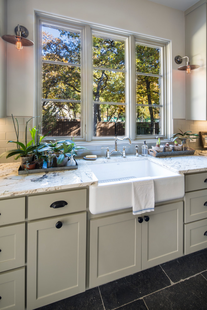 Mid-sized country l-shaped dedicated laundry room in Dallas with a farmhouse sink, shaker cabinets, white cabinets, marble benchtops, white walls, slate floors and a side-by-side washer and dryer.