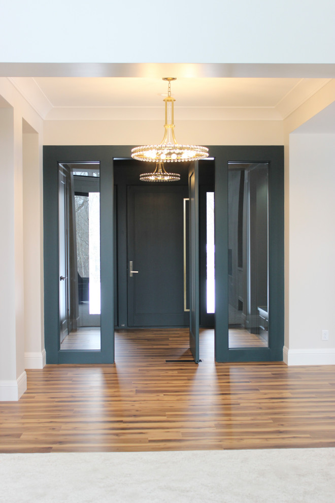 Foto de vestíbulo minimalista con paredes verdes, suelo de madera en tonos medios, puerta simple y madera