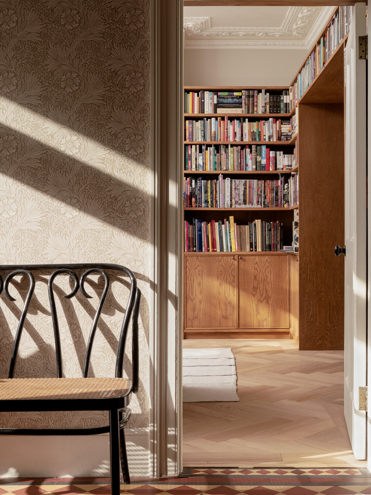 Immagine di un soggiorno american style chiuso con libreria, pareti beige, pavimento in legno massello medio, stufa a legna, cornice del camino in pietra, TV nascosta e pannellatura
