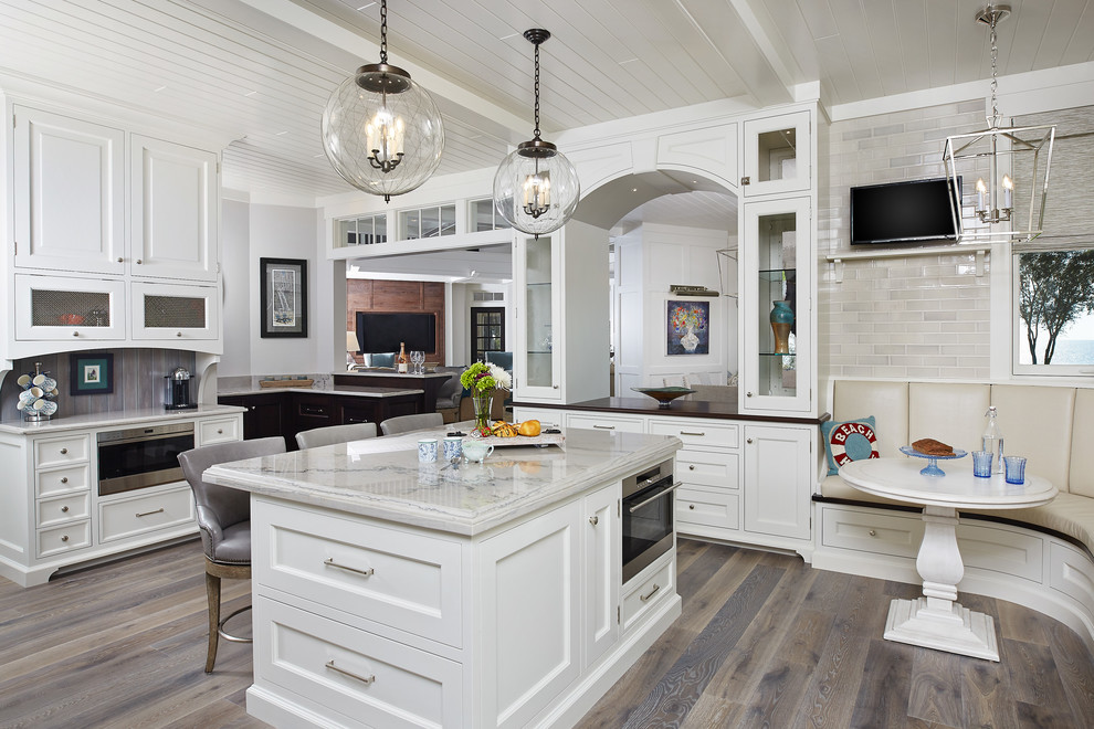Inspiration for a beach style kitchen in Grand Rapids with recessed-panel cabinets, white cabinets, stainless steel appliances, medium hardwood floors, with island and grey floor.