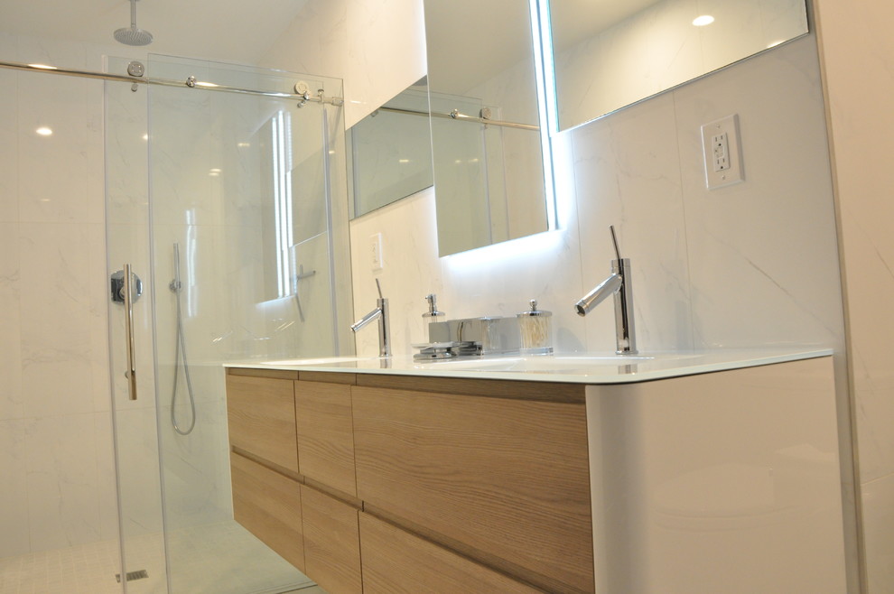 Inspiration for a mid-sized contemporary master bathroom in Philadelphia with medium wood cabinets, an open shower, a one-piece toilet, white tile, ceramic tile, white walls, porcelain floors, an integrated sink and glass benchtops.