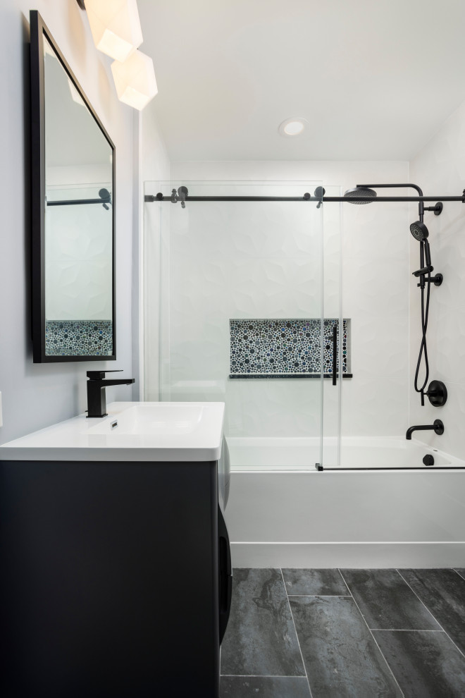 Idées déco pour une salle de bain contemporaine de taille moyenne avec des portes de placard grises, une baignoire posée, un combiné douche/baignoire, WC à poser, un carrelage noir, des carreaux de céramique, un mur gris, un sol en carrelage de porcelaine, un lavabo posé, un plan de toilette en surface solide, un sol noir, un plan de toilette blanc, une niche, meuble simple vasque et meuble-lavabo suspendu.