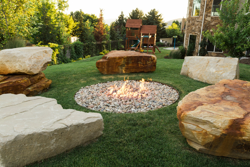 Large traditional backyard garden in Salt Lake City with a fire feature and river rock.