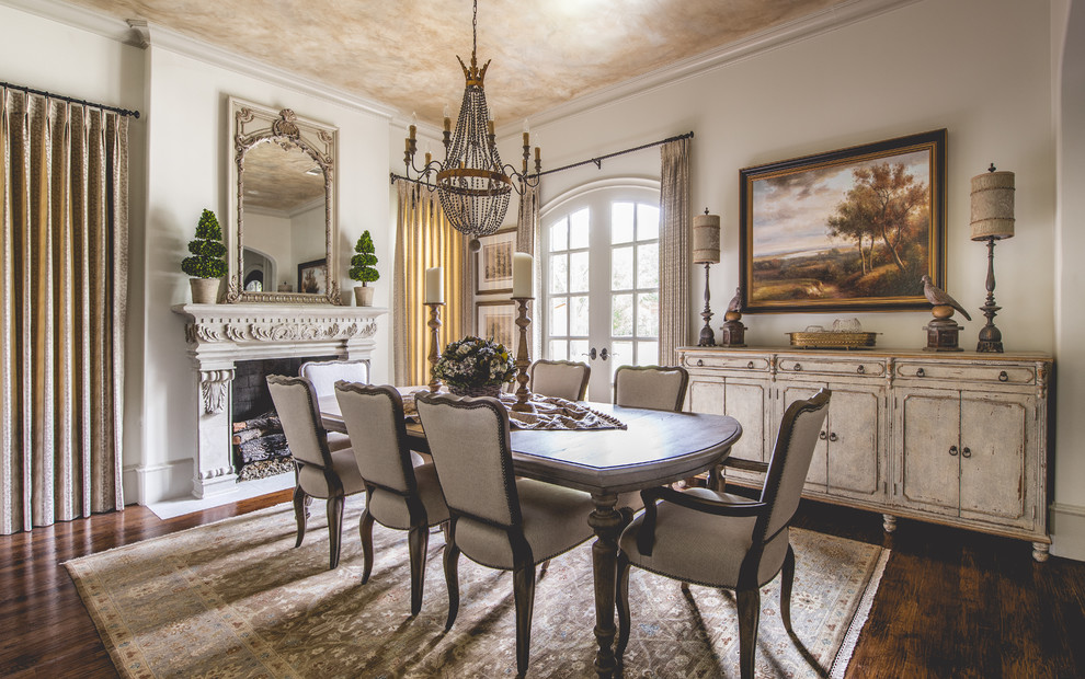 Photo of a large mediterranean separate dining room in Dallas with white walls, medium hardwood floors, a standard fireplace and a plaster fireplace surround.