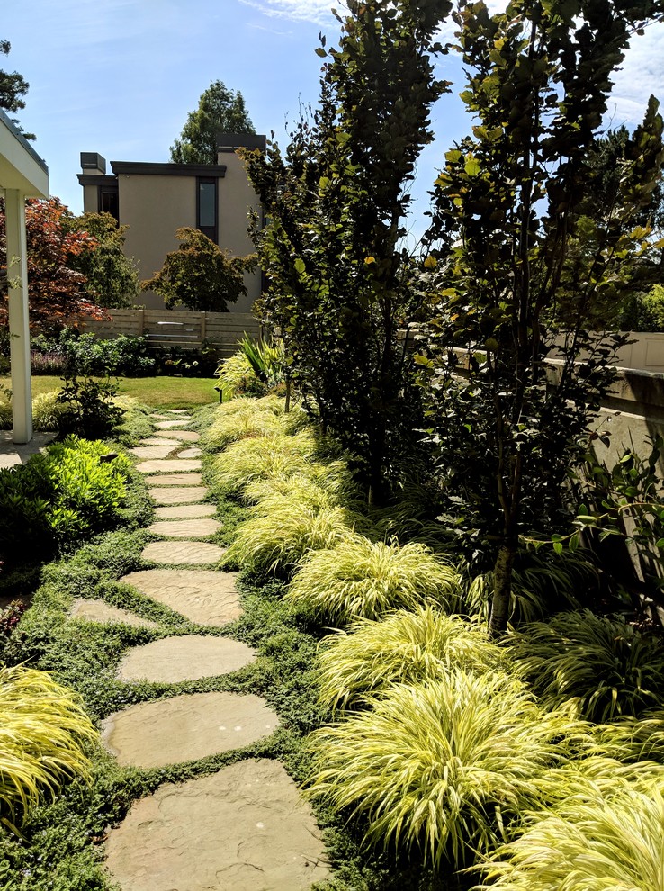 Photo of a modern side yard partial sun garden for summer in Seattle with natural stone pavers.