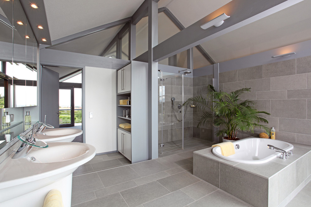 This is an example of an expansive contemporary bathroom in Stuttgart with open cabinets, white cabinets, a drop-in tub, a curbless shower, gray tile, stone tile, grey walls and an integrated sink.