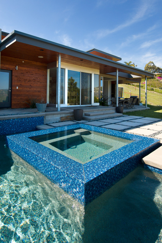 This is an example of a modern backyard custom-shaped pool in San Diego with a hot tub and tile.