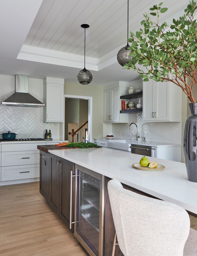 Large transitional u-shaped light wood floor, brown floor and coffered ceiling eat-in kitchen photo in Chicago with a farmhouse sink, shaker cabinets, white cabinets, quartz countertops, white backsplash, subway tile backsplash, stainless steel appliances, an island and multicolored countertops