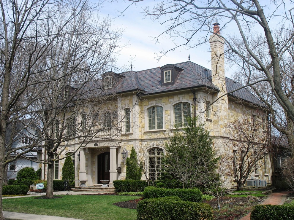 Photo of a large mediterranean three-storey multi-coloured exterior in Chicago with stone veneer and a hip roof.