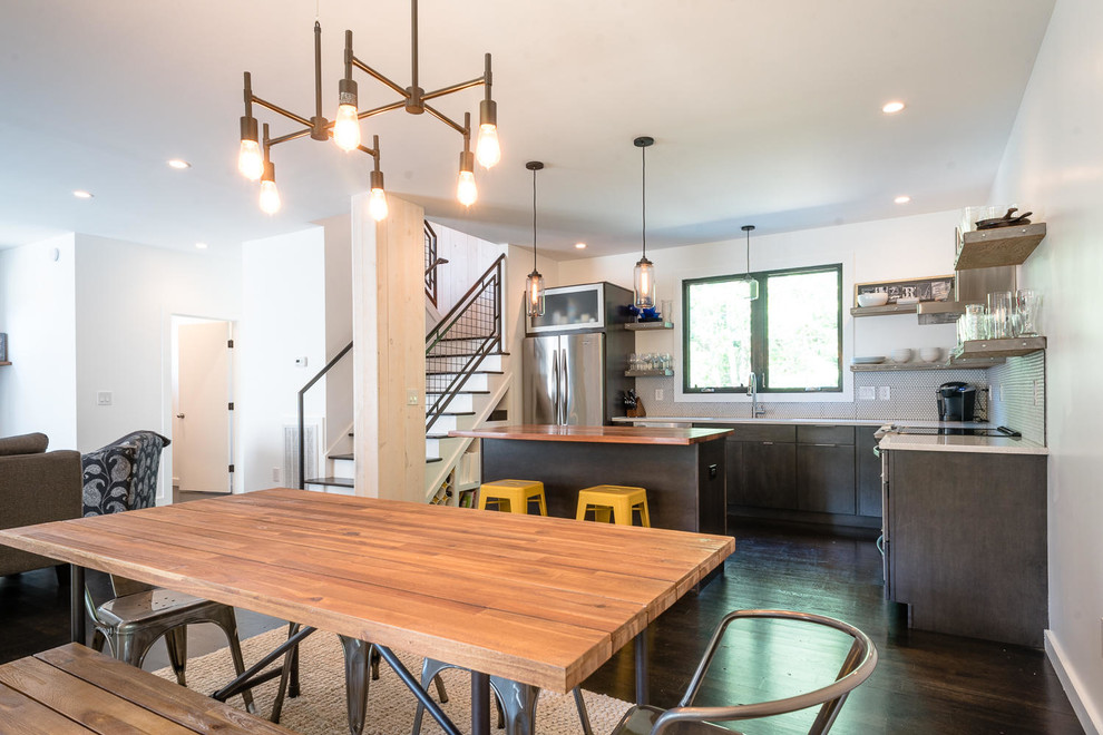 Example of a trendy dark wood floor and black floor kitchen design with ceramic backsplash, stainless steel appliances and an island