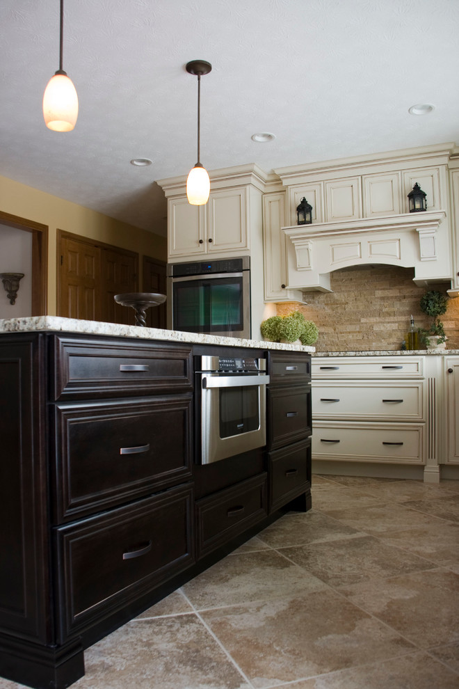 Eat-in kitchen - large u-shaped ceramic tile eat-in kitchen idea with a farmhouse sink, recessed-panel cabinets, distressed cabinets, granite countertops, beige backsplash, stone tile backsplash, stainless steel appliances and an island