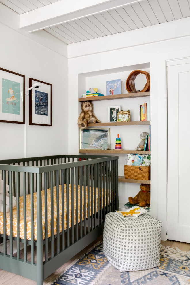 Laguna Bungalow - Example of a beach style medium tone wood floor, brown floor, exposed beam and shiplap ceiling nursery design in Orange County with white walls