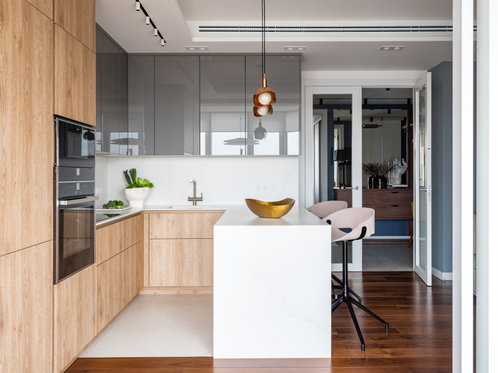 Photo of a medium sized contemporary u-shaped kitchen/diner in Moscow with a submerged sink, flat-panel cabinets, light wood cabinets, white splashback, an island and white worktops.